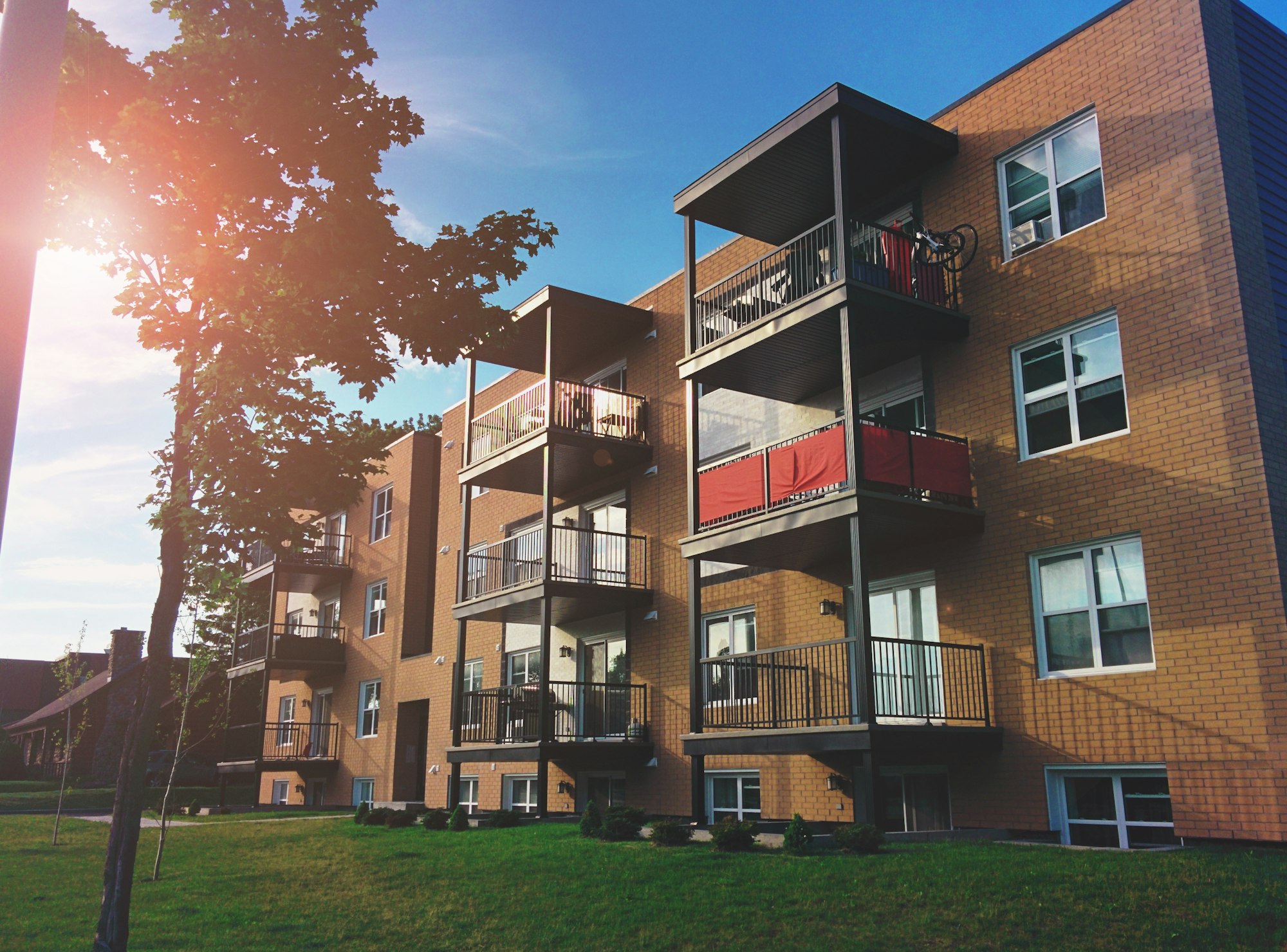 Garden-style brick apartment community with balconies and lawn